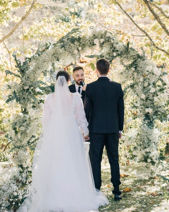 Dyego Inácio celebrando uma cerimônia de casamento sob arco de flores